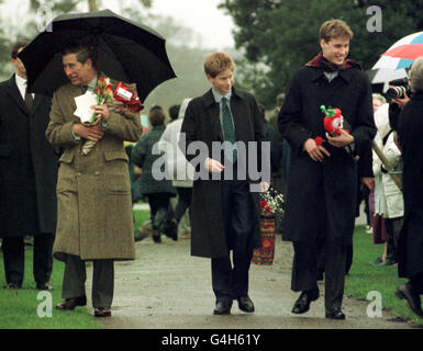 Der Prinz von Wales und seine Söhne, die Prinzen William (R) und Harry, tragen Geschenke, die sie von Brunnenflüchtlern erhielten, als sie die Kirche auf dem Sandringham Estate nach dem traditionellen Weihnachtsgottesdienst verlassen. Stockfoto