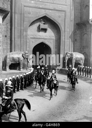 König George V, der in einer Prozession durch ein Mughal-Tor am Roten Fort, Delhi, von britischen Truppen flankiert reitet. Stockfoto