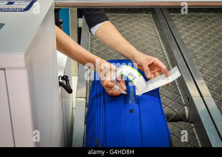 Check-in Mitarbeiter legt ein Gepäckanhänger Koffer von Passagier - Nahaufnahme von Händen Stockfoto