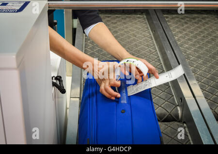 Check-in Mitarbeiter legt ein Gepäckanhänger Koffer von Passagier - Nahaufnahme von Händen Stockfoto