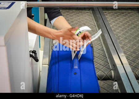 Check-in Mitarbeiter legt ein Gepäckanhänger Koffer von Passagier - Nahaufnahme von Händen Stockfoto