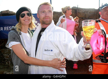 Ronan Keating wird von seiner Frau Yvonne begrüßt, als er am 40 Meter langen Hafen in Dublin ankommt, während er und andere Schwimmer das Schwimmen beenden - ein Spendenschwimmen über die Irische See zugunsten von Cancer Research UK. Stockfoto