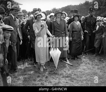 Der Herzog und die Herzogin von York (später Königin Elizabeth und König George VI) und die Kinder des Fresh Air Fund im Epping Forest. Die herzogin versucht sich an der Kokosnuss schüchtern. Stockfoto