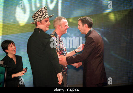 Big Breakfast-Moderator Johnny Vaughan schüttelt sich die Hände mit Norman Cook (Fatboy Slim), der den Preis für den besten Tanz bei den Brit Awards in der London Arena gewann. Boy George und Sharleen Spiteri von der Band Texas, teilen das Lachen auf der Bühne. Stockfoto