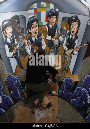 Der aus Mexiko stammende 3D-Straßenmaler Juandres Vera verleiht dem weltweit ersten dualen anamorphen 3D-Straßenkunstwerk mit den Beatles in Liverpool den letzten Schliff. Stockfoto