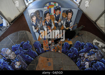 Der aus Mexiko stammende 3D-Straßenmaler Juandres Vera verleiht dem weltweit ersten dualen anamorphen 3D-Straßenkunstwerk mit den Beatles in Liverpool den letzten Schliff. Stockfoto