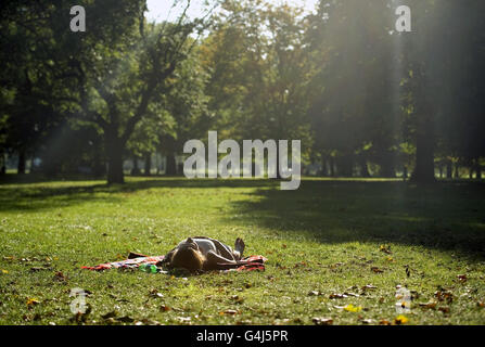 Ein Mitglied der Öffentlichkeit entspannt sich in der warmen Abendsonne auf Clapham Common, London. Stockfoto