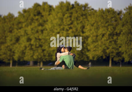 Ein Paar umarmt in der warmen Abendsonne auf Clapham Common, London. Stockfoto