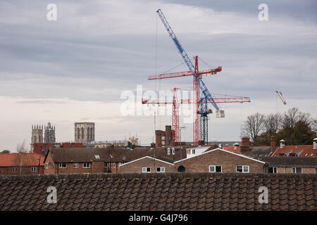 Blick über die Dächer in York, North Yorkshire, England - 3 alten Minster Türmen und 3 modernen Kränen, die Häuser überragt. Stockfoto