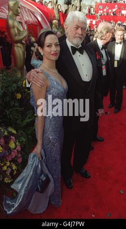 Oscar-Preisträger James Coburn kommt mit seiner Frau Paula Murad zu den 71. Jährlichen Academy Awards im Dorothy Chandler Pavilion in Los Angeles an. Coburn wurde für seine Rolle im Film „Affliction“ als bester Supprting Actor ausgezeichnet. Stockfoto