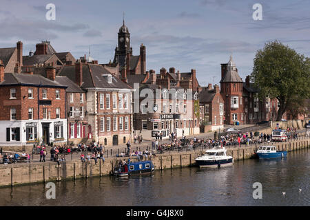 Viele Leute trinken und entspannen in der Sonne in geschäftigen Pubs am Flussufer und Freizeitboote, die auf dem Fluss Ouse - King's Staith, York, North Yorkshire, England - festgemacht sind. Stockfoto