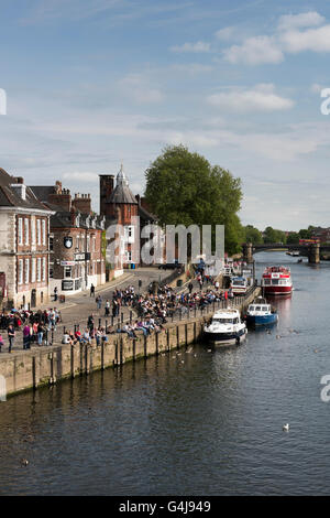 Viele Leute trinken und entspannen in der Sonne in geschäftigen Pubs am Flussufer und Freizeitboote, die auf dem Fluss Ouse - King's Staith, York, North Yorkshire, England - festgemacht sind. Stockfoto