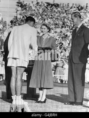 Die Königin, die vom Duke of Edinburgh beobachtet wird, präsentiert dem jungen australischen Tennisstar Mervyn Rose während des Rouyal-Besuchs auf den Kooyong Tennisplätzen in Melbourne einen Salver. *beschädigte Platte* Stockfoto