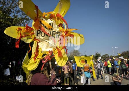 Ein Protestor hält ein sonnenförmiges Banner wie mehrere Anti-Atomgruppen, die Teil des Stop New Nuclear Alliance Protest vor Hinkley Point Kraftwerk in Somerset gegen EDF Energy Pläne, den Standort mit zwei neuen Reaktoren zu erneuern. Stockfoto