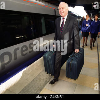 Sir John Egan, der während der Versuche zur Eröffnung des weltweit größten Remote-Terminals, des neuen BAA Heathrow Express Check-in, am Bahnhof Paddington ankommt, der 27 Check-in-Schalter aller großen Fluggesellschaften umfassen wird. * Hintergrund zeigt zwei uniformierte Heathrow Express Mitarbeiter Caterine Well (L) und Debbie Syme (R). Der Check-in ist ab 23 1999. Juni möglich Stockfoto