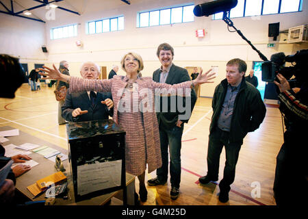 Die Frau des Präsidentschaftskandidaten Michael D. Higgins (links), Sabina Coyne, wirft ihre Arme aus, als ihre Söhne Daniel (rechts) und Micheal Jnr (zweite rechts) an der St.James National School, Bushy Park, Galway, wählen, während Wähler in ganz Irland heute zur Wahl des neunten Präsidenten des Landes gehen. Stockfoto
