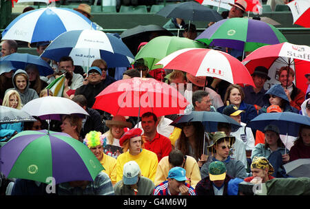 Keine kommerzielle Nutzung: Tennisfans decken sich unter Regenschirmen ab, nachdem Regen aufhört, während des vierten Tennisspiels zwischen Andre Agassi und Wayne Arthurs auf dem Court One in Wimbledon zu spielen. Stockfoto