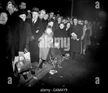 Ein glücklicher Schlange, ein kleiner Junge, sitzt bequem auf einem Lagerhocker, als er mit 100,000 anderen Briten an der Reihe ist, um an dem drapierten Sarg in Westminster Hall vorbei zu kommen und König George VI. Einen letzten Tribut zu zollen Die Schlange war über vier Meilen lang. Stockfoto