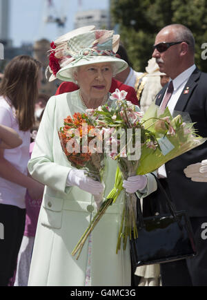 Königin Elizabeth II. Hält Blumen, die ihr von Menschenmengen in Brisbane, Australien, geschenkt wurden. Stockfoto