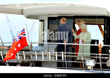 Queen Elizabeth II (rechts) winkt den riesigen Menschenmassen am Ufer des Brisbane River zu, während sie und der Duke of Edinburgh (zurück zur Kamera) auf dem Motorcruiser Pure Adrenalin in in Brisbane, Australien, den Fluss hinunter fahren. Stockfoto