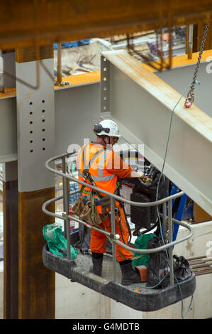 Bauarbeiter in einem Hebezeug Installation Stahlträger an Eastern Schalterhalle der Crossrail, Farringdon Station, London Stockfoto