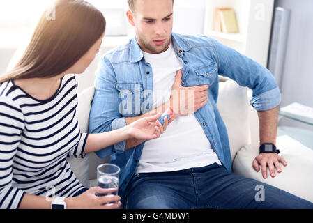 Kranker Mann mit seiner Freundin auf der Couch sitzen Stockfoto
