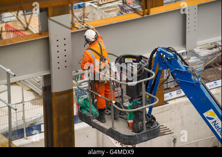 Bauarbeiter mit einem Hebezeug Träger auf der östlichen Schalterhalle Website unter Crossrail-Bahnhof Farringdon, London zu installieren Stockfoto