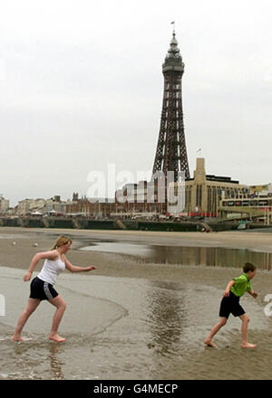 Zwei Urlauber trotzen den eisigen Bedingungen in Blackpool und paddeln im Meer, während die Temperaturen im Norden am Montag, den 31 1999. Mai, niedrig bleiben. Stockfoto