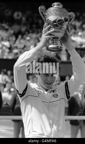 Der amerikanische Tennisspieler John McEnroe hält sich nach dem Sieg im Finale der Herren an der Wimbledon Trophy fest. Stockfoto