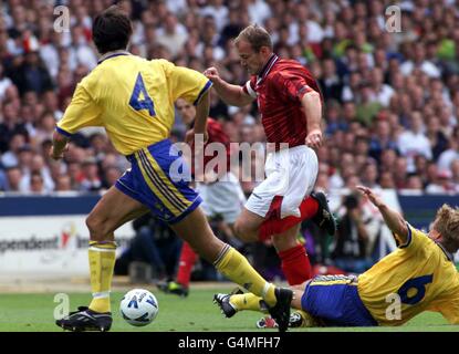 Der englische Alan Shearer (C) läuft mit dem Ball, während der Schwede Stefan Schwarz (R) während des Euro-2000-Gruppenspiel 5 im Wembley-Stadion ins Spiel rutscht. Endstand: England 0 Schweden 0. Stockfoto