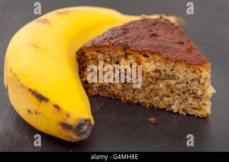 frisch zubereitete Bananenkuchen und überreife Bananen auf schwarze Schieferoberfläche Stockfoto