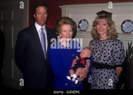 Premierministerin Margaret Thatcher kradelt ihren Enkel Michael in der Downing Street 10. Ebenfalls abgebildet sind die Eltern des Säuglings, Mark (Sohn von Margaret Thatcher) und seine Frau Diane (geb. Burgdorf). Stockfoto