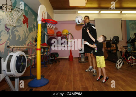 Peter Murchie, der Spieler der Glasgow Warriors, wird mit dem fünfjährigen Greg Steven abgebildet, der Tests durchläuft, nachdem Ärzte während einer Ankündigung im Royal Hospital for Sick Children in Glasgow entzündetes Hirngewebe entdeckt hatten. Stockfoto