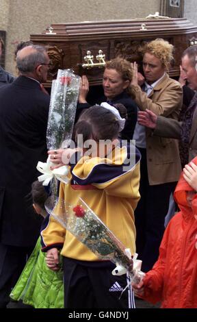 Der Sarg von Eamon Malloy wird von weiblichen Mitgliedern seiner Familie aus seinem Familienhaus in Belfast getragen, da kleine Kinder eine einzelne rote Rose vor dem Sarg tragen. Molloy war ein angeblicher IRA-Informer und wurde 1975 von der IRA getötet. * ...sein Leichnam wurde als erster von der IRA an seine Familie zurückgegeben, als er auf einem Friedhof in der Nähe der Grenze zurückgelassen wurde. Eamon Molloy, wird in einem Familiengrundstück auf dem Stadtfriedhof nach Requiem in der Sacred Heart Church in Ardoyne beigesetzt. Stockfoto