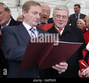 Taoiseach Enda Kenny (links) und Tanaiste Eamon Gilmore (rechts) singen Weihnachtslieder vor dem Leinster House in Dublin, nachdem die Weihnachtsbaumlichter von Ceann Comhairle Sean Barrett eingeschaltet wurden. Stockfoto