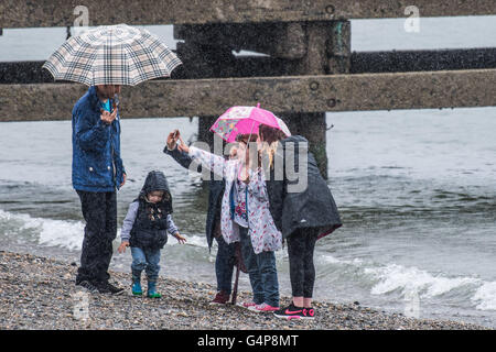 Aberystwyth, Wales, UK. 19. Juni 2016. UK-Wetter: Eine Familie nehmen eine Gruppe Selfie bergende unter ihren Sonnenschirmen, wie sie entlang am Meer in Aberystwyth auf einem nassen und kalten Sonntagnachmittag Mitte Juni gehen.    Als der längste Tag des Jahres - der Sommer-Sonnenwende - Ansätze, eine Bande von Starkregen fegt aus dem Westen, die meisten des Vereinigten Königreichs in den kommenden Tagen Credit ungewöhnlich kalte und bewölkte Bedingungen bringen: Keith Morris/Alamy Live-Nachrichten Stockfoto