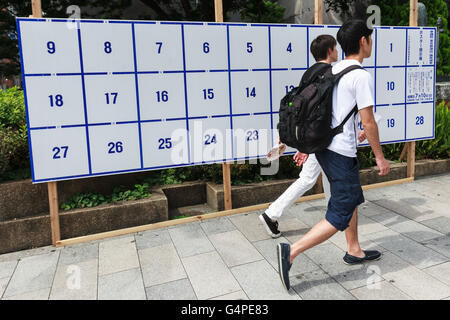 Fußgänger gehen vorbei an einem Plakat Bord speziell für Wahl-anzeigen bereit, Kandidaten Plakate für Julys Oberhaus Wahlen auf dem Display in Tokios Straßen am 20. Juni 2016, Japan errichtet. Im Vorfeld des 10. Juli Umfrage Kandidaten gehen durch die Straßen, das Aufstellen von Plakaten, hielt Reden und halten Kundgebungen, um ihre Politik zu präsentieren. In diesem Jahr Zielen die politischen Parteien Jungwähler, im Alter von 18 und 19 jährigen, die zum ersten Mal abstimmen dürfen. © Rodrigo Reyes Marin/AFLO/Alamy Live-Nachrichten Stockfoto