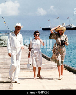 Prinzessin Margaret, Mitte, und ihre Freunde Lady Ann Tennant und Lord Colin Tennant warten auf dem Anlegesteg in Mustique, um Königin Elizabeth II. Während ihrer Silberjubiläum-Tour durch die Westindischen Inseln zu begrüßen. Die Royal Yacht Britannia ist im Hintergrund. Stockfoto