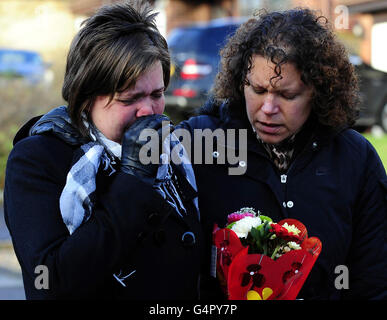 Cheryl Heights (links) und Sara Turnbull bringen Blumen in die Szene in der Nähe des Hauses in Pudsey, Leeds, wo am späten Sonntagnachmittag vier Leichen entdeckt wurden. Stockfoto