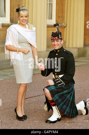 Der Privatmann Bryan Johnson vom Royal Regiment of Scotland geht auf ein Knie, nachdem er während einer Investiturzeremonie im Buckingham Palace, London, Kirstie ward, als Verlobten vorgeschlagen hatte, wo er vom Prince of Wales mit dem Militärkreuz ausgezeichnet wurde. Stockfoto