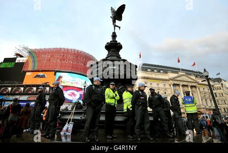 Die Polizei wacht über Demonstranten, die vermutlich aus UK Uncut stammen, versammelten sich im Piccadilly Circus, London, als eine kleine Anzahl von Demonstranten heute ein Büro im Londoner West End stürmten, da Angestellte des öffentlichen Sektors in Großbritannien heute den größten Generalstreik seit Jahrzehnten in Folge über Renten verübten. Stockfoto