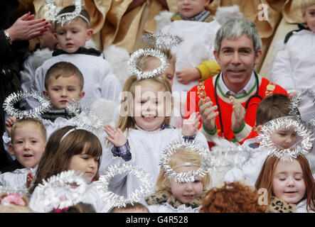 Oberbürgermeister Andrew Montague begleitet als Engel gekleidete Kinder von der St. Josephs Nursery zum Singen von Weihnachtsliedern, da die traditionelle lebende Tierkrippe, die von der Irish Farmers Association bereitgestellt wird, im Herrenhaus in Dublin eröffnet wird. Stockfoto