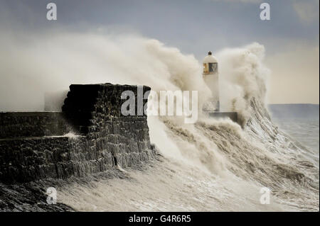 Riesige Wellen stürzen gegen die Hafenmauer und verschlingen den Leuchtturm in Porthcawl, South Wales, während starke Winde und Regen den Südwesten Großbritanniens überschwemmen. Stockfoto