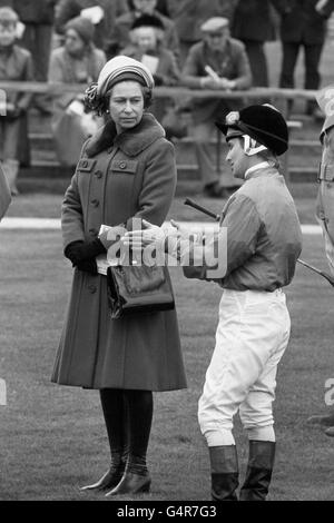 Die Königin hört zu, wie Jockey Willie Carson mit ihr im Fahrerlager plaudert, bevor er Sea Boat, einen hengst, den sie letztes Jahr gekauft hatte, auf den dritten Platz im Ladbroke Racing Handicap bei Newmarket brachte. Stockfoto