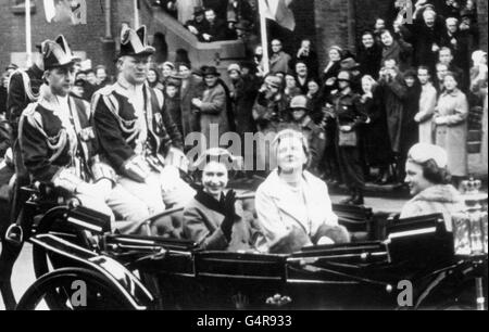 Königin Elizabeth II. Lächelt und winkt, als sie in einem offenen Wagen mit Königin Juliana und Prinzessin Irene vom Landeplatz in Amsterdam zum Königspalast fährt, als sie mit dem Herzog von Edinburgh zu einem dreitägigen Staatsbesuch in Holland ankommt. Stockfoto