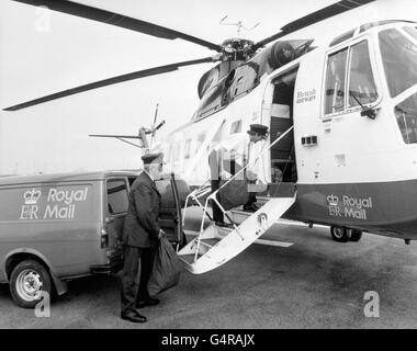 Der Hubschrauber von British Airways Mail wurde in Penzance von Postbote Dudley Richard (r) mit Post für die Scilly Isles beladen. Es ist der einzige Hubschrauber-Postdienst des Postamtes in Großbritannien und befördert 15,000 Briefe und Pakete pro Monat. Das Flugzeug bringt Passagiere auch auf dem 30 Meilen langen Flug nach St. Mary's, der größten der Inseln Stockfoto