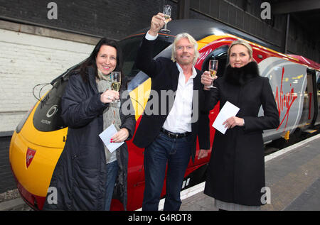 Virgin Trains-Kunden Helen Pratt (links), der drei Monate lang kostenlose Zugreisen der ersten Klasse angeboten wurden, und Lyudmila Percival (rechts), der von Sir Richard Branson (Centre), Gründer der Virgin Group of Companies am Bahnhof Euston im Zentrum von London, einen Urlaub in Dubai überreicht wurde. Stockfoto