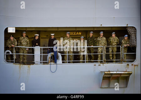 Militärangehöriger beobachten von der HMS Ocean aus, wie sie in die Docks des Royal Naval Base Devonport Plymouth einzieht, nach einer siebeneinhalbmonatigen Tour, bei der die Besatzung Luftangriffe gestartet hat, die das Regime von Oberst Gaddafi in Libyen beenden halfen. Stockfoto