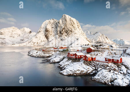 Stadt und Fischers Kabinen oder Federbett vor schneebedeckten Bergen, winter, Sakrisøya, Moskenesøy, Lofoten, Norwegen Stockfoto