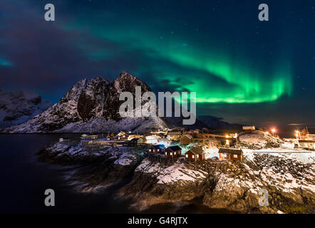 Stadt und Fischers Kabinen oder Federbett vor schneebedeckten Bergen, Aurora Borealis, Winter, Sakrisøya, Moskenesøy, Lofoten Stockfoto